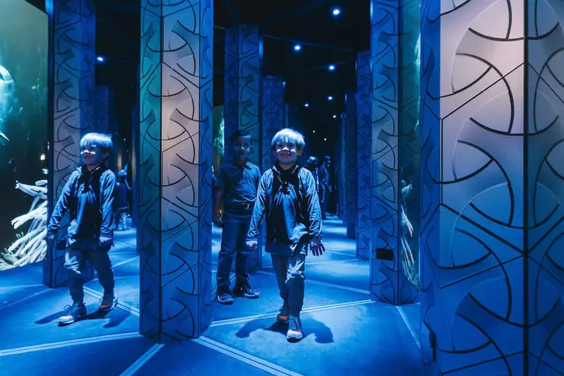 Two children walking through a hall of mirrors and smiling.