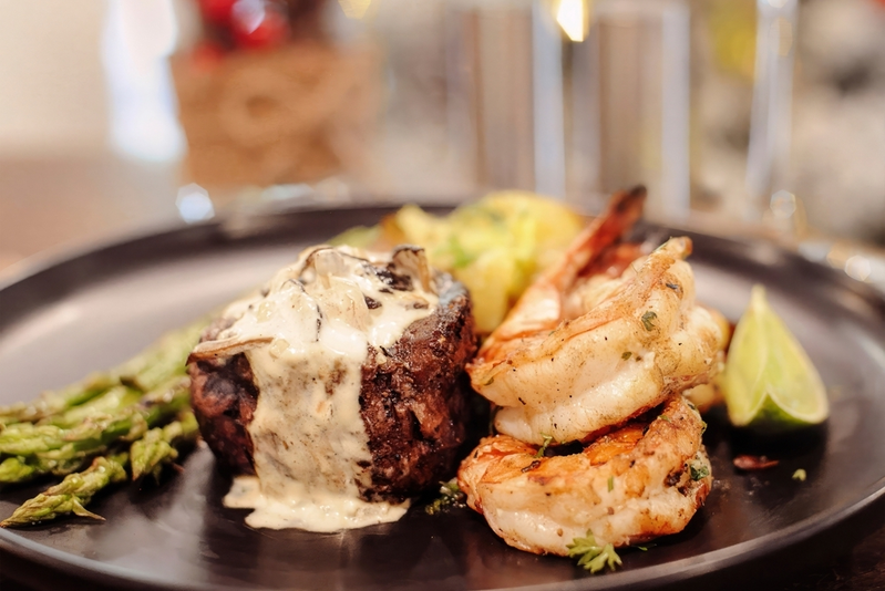 A plate of surf and turn with steak and shrimp and a side of asparagus.